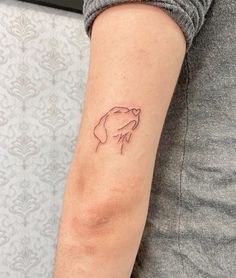 a woman's arm with a small tattoo of a dog on the left side of her arm