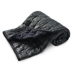 a black blanket folded on top of a white surface with the cover pulled up to reveal a quilted design