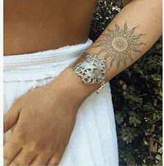 a woman with a tattoo on her arm wearing a white dress and holding onto the wrist