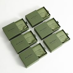 six green boxes sitting next to each other on top of a white surface with the lids open