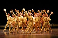 a group of people on stage with their arms in the air holding up pots and pans