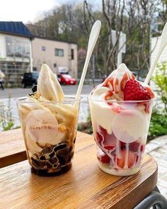 two desserts sitting on top of a wooden table next to each other in cups