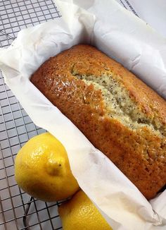 a loaf of lemon bread sitting on top of a cooling rack next to two lemons