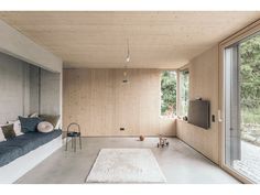 a living room with wood paneling and large windows on the side of the wall