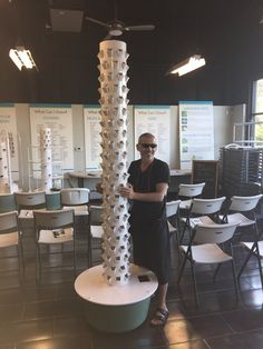 a man standing in front of a tall tower made out of toilet rolls and cups