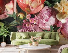 a living room with flowers on the wall and green couches in front of it