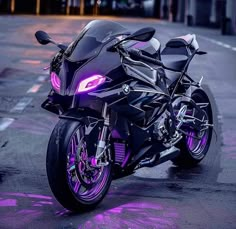 a black motorcycle parked on the street with purple light around it's tires and headlight