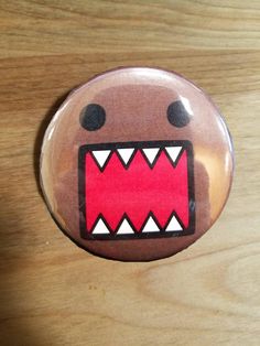 a close up of a button on a wooden surface with an angry face and teeth