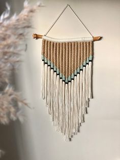 a wall hanging made with macrame and wood beads, on a white wall