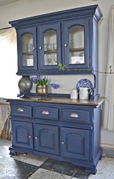 a blue china cabinet with glass doors and drawers