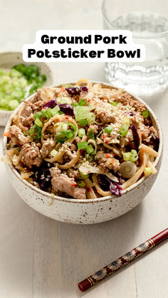 a bowl filled with meat and vegetables next to chopsticks on a table top