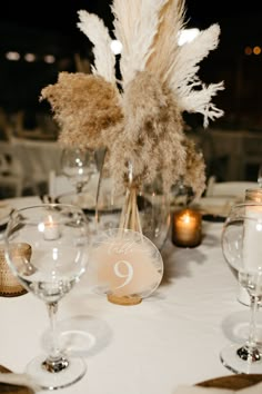 the table is set with wine glasses, candles and pamylum centerpieces