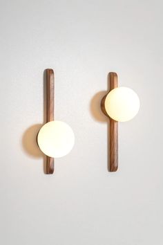 two wall lights mounted to the side of a white wall next to a wooden pole