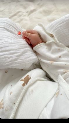 a baby is wrapped in a blanket and laying on it's side with its hand resting on the pillow