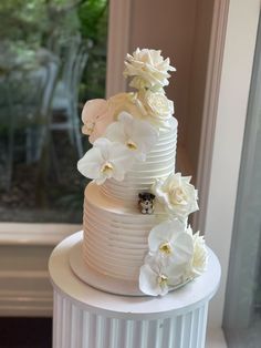 a three tiered cake with white flowers on top