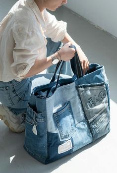 a woman sitting on the floor holding a blue jean tote bag in her hands