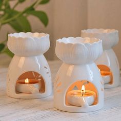 three white ceramic candle holders sitting on top of a table