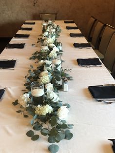 a long table with white flowers and candles on it