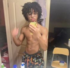 a shirtless man taking a selfie in front of a mirror with his cell phone