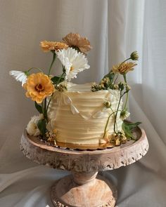 there is a cake with flowers on the top and bottom layer, sitting on a stand