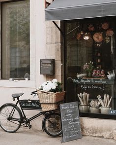 a bicycle parked in front of a store with a basket full of food on it