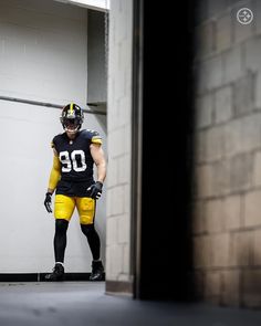 a football player is dressed in black and yellow uniform with his hands on his hips