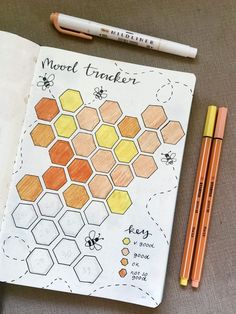 an open notebook with honeycombs and pencils next to it