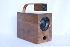 a wooden box with two speakers in it on a white background and one speaker is attached to the back of the box