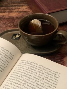 an open book on a tray next to a cup of tea