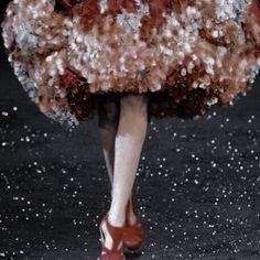 a woman is walking down the runway in a dress made out of flowers and feathers