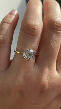 a woman's hand with a diamond ring on top of her finger, showing the center stone