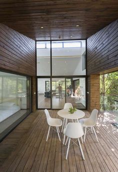 a white table and chairs on a wooden floor in front of a large glass window