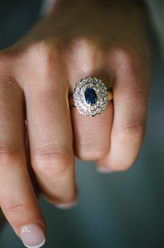 a close up of a person's hand with a diamond and sapphire ring on it