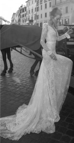 a woman standing next to a horse drawn carriage on a city street in black and white