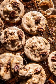 several donuts with icing and pecans on a cooling rack