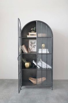 a book shelf with books on top of it and an arched glass door in the middle