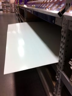 an empty shelf in a store filled with lots of white paper on it's sides