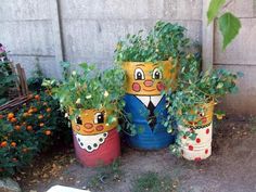 three painted pots with plants in them on the ground