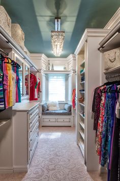 a walk in closet with lots of clothes hanging on the walls and drawers, along with a window seat