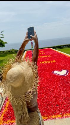 a woman taking a photo with her cell phone in front of a field of flowers