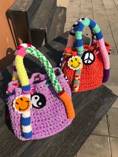 two crocheted purses sitting on top of a wooden bench next to each other