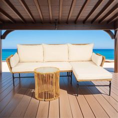 a white couch sitting on top of a wooden floor next to a table and ocean