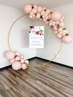 a welcome sign and balloon arch in a room with wood flooring for baby shower