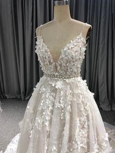 a white dress with flowers on the skirt is displayed in front of a mannequin