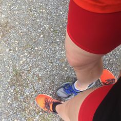 the bottom view of a person's legs and feet with red shorts on, standing in gravel