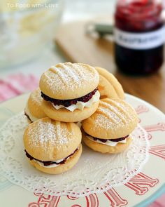 some cookies are sitting on a plate with powdered sugar and jam in the background