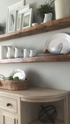 two wooden shelves above a table with plates and bowls on it, one shelf holding dishes