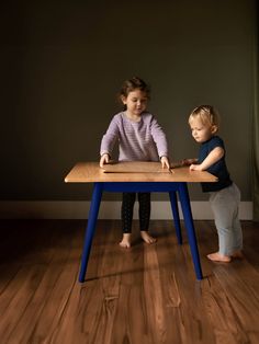 two young children playing with a wooden table