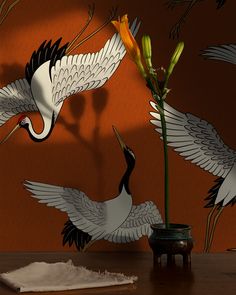 two white birds flying over a flower in a vase