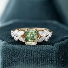 a green and white ring sitting on top of a blue velvet box with its lid open